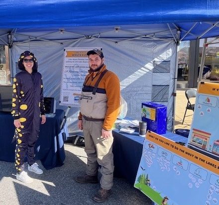 Two people standing under a tent.